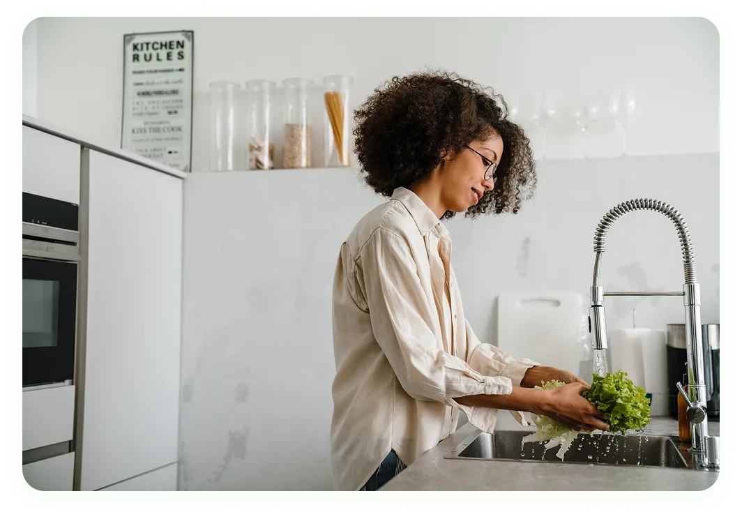 Household help washing vegetables in kitchen